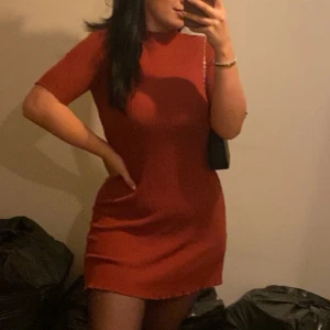 Rostfärgad klänning - Snygg rostfärgad klänning med korta ärmar och en figurnära passform. Perfekt för en kväll ute eller en speciell tillställning. Enkel och stilren design som är lätt att matcha med accessoarer.