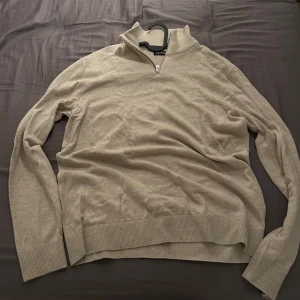 Beige tröja med dragkedja från Jack & Jones - Säljer en stilren beige tröja från Jack & Jones med dragkedja vid halsen. Tröjan har långa ärmar och ribbade muddar vid ärmslut och nederkant. Perfekt för en avslappnad look.