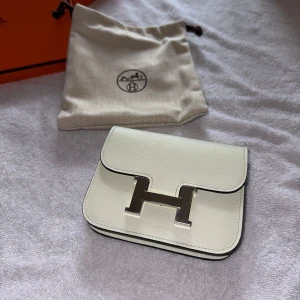 Veau Fizz Constance Slim Compct plånbok från Hermès - Elegant ljusgrön från Hermès i skinn med en ikonisk H-detalj på framsidan. Den kompakta designen gör den perfekt för att bära med sig det viktigaste. Levereras med dustbag och original låda. Plånboken är helt oanvänd, inköpt på Hermès i Stockholm. Kvitto finns såklart.