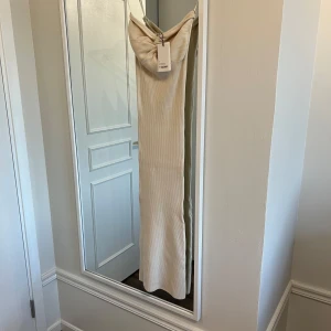 Beige ribbad klänning från By Lovisa Barkman  - Beige ribbad tub klänning med en knutdetalj i fram. Från Lovisa Barkman x Bikbok, mjukt stretchigt material. Aldrig använd prislapp sitter fortfarande på. I storlek S