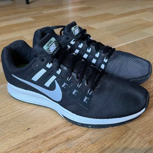 Svarta Nike sneakers zoom structure h2o repel - Snygga svarta Nike zoom structure h2o repel med stable run sula och dynamic support häl. vit sula och klassisk snörning. Skorna har en stilren design med Nike-loggan på sidan och är perfekta för både träning och vardag. De har en bekväm passform. Skiftar lite i färg i solljus som är rätt coolt. Nypris 1300-1600 . Sparsamt använda 