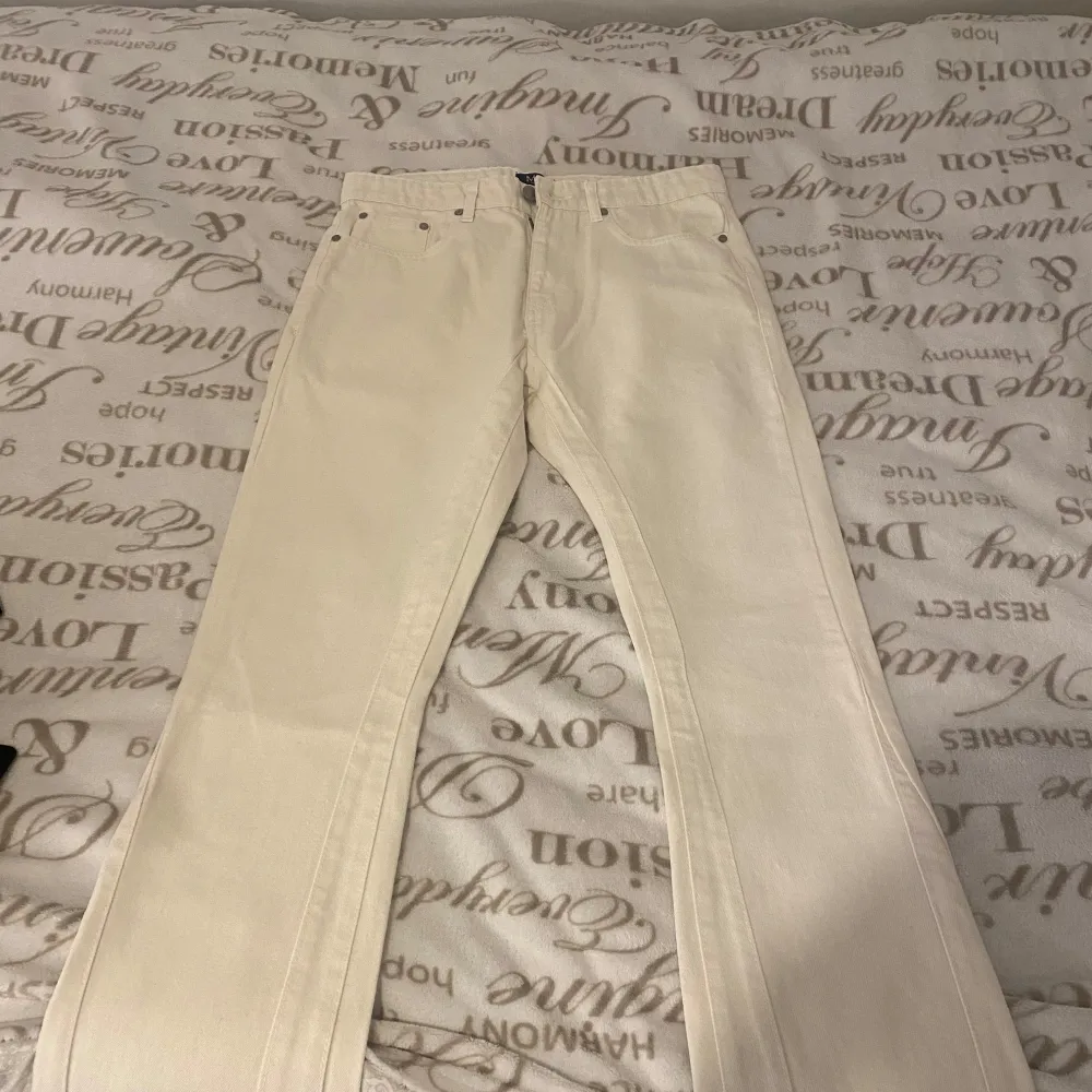 Två par byxor till salu. Ett par vita byxor med bootcut-stil och ett par svarta byxor med broderade detaljer i silver. De svarta byxorna har en unik design med dekorativa mönster längs benen.pris diskuteras dm😍300st och båda 500kr. Farkut & Housut.