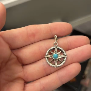 Thomas SABO berlock - Snyggt kompasshänge i silver med en turkos sten i mitten. Hänget har en stjärnformad design och är dekorerat med små glittrande stenar runt om.  Nypris ca 980 kr.