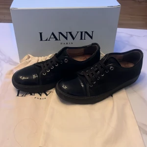 Svarta lanvins - Snygga svarta sneakers från Lanvin med glansig tå och snörning. Perfekta för en stilren look. Skorna kommer med originalförpackning och dustbags. Skick skulle jag påstå vara 8/10 generellt dock är de ett hål under sulan på högra skon men inget som syns eller märks under användning. Kan även tänka mig byten mot giuseppe zanotti skor och även valentino flycrews har man fler funderingar höra gärna av dig då!🤩💗