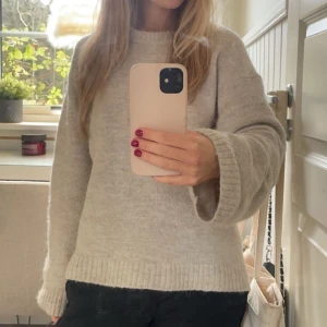 Stickad tröja från Gina - Mysig beige stickad tröja från Gina tricot med rund hals och långa ärmar. Perfekt för kyliga dagar med sin mjuka och bekväma passform. Ribbstickade muddar vid ärmslut och nederkant ger en klassisk look.