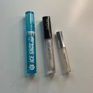 Tre läppglans i olika nyanser - Säljer tre läppglans: W7 Ice Shot med plumpingeffekt i en blå förpackning, IsaDora Liquid Lip Glow i en genomskinlig tub, och Cloudy Dream i en silverfärgad hylsa. Perfekta för att ge läpparna en glansig finish. Knappt använda