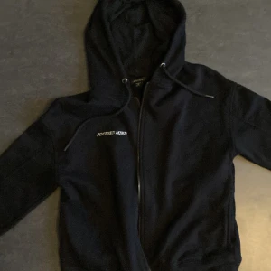 Svart hoodie från Amisu - Säljer en svart hoodie från Amisu med texten 'FOCUSED MIND' broderad på bröstet. Den har en dragkedja framtill och en bekväm huva med snörning. Perfekt för en avslappnad stil.