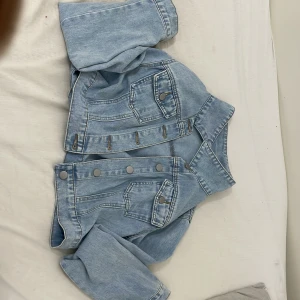 Ljusblå jeansjacka - Säljer en snygg ljusblå jeansjacka med knappar framtill och klassiska bröstfickor. Jackan har en kort passform och långa ärmar. Perfekt för vår och sommar! 💙