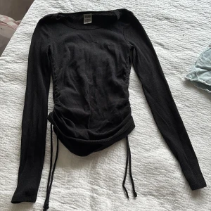 Svart ribbad tröja från Victoria's Secret PINK - Säljer en svart ribbad tröja från Victoria's Secret PINK. Tröjan har långa ärmar och snörning i midjan för en justerbar passform. Perfekt för en stilren look.