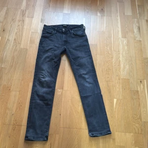 Svarta jeans från Jack & Jones - Snygga svarta jeans från Jack & Jones i modellen Regular/Clark. De har en klassisk femficksdesign och stängs med dragkedja och knapp. Perfekta för en stilren look.