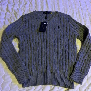 Grå stickad tröja från Ralph Lauren - Helt oanvänd,  Mycket bra kvalité och lapparna är kvar. mycket varm och är perfekt för lite kyligare väder. Ett perfekt plagg för din garderob