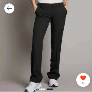 Svarta kostymbyxor - Snygga svarta kostymbyxor med en klassisk straight passform. De har en midwaist design och är perfekta för en stilren look. Byxorna har knappar och dragkedja framtill för enkel stängning.