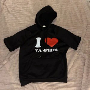 Svart hoodie med tryck - Säljer en svart hoodie och ett coolt tryck som säger 'I ❤️ VAMPIRES'. Perfekt för dig som älskar vampyrer! Tillverkad i 100% polyester och har en bekväm passform med huva.
