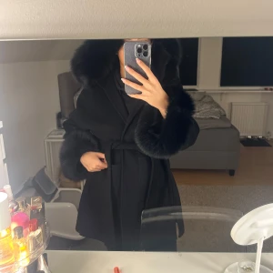 Svart kappa med pälsdetaljer - Nu säljer jag denna fina kappan eftersom den vart till användning en två gånger och sedan bara hängt i min garderob. Köpte den från femenina. Xs/s