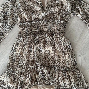 Leopardmönstrad klänning - Trendig leopardmönstrad klänning med v-ringning och långa ärmar. Den har en smockad midja som ger en fin passform och volangdetaljer vid fållen. Perfekt för att sticka ut med stil! Från Zara i strl M och har för mig att jag sytt in den lite i midjan och passar mig som brukar ha mellan xs-s💞❤️