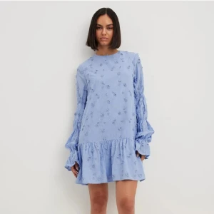 Ljusblå klänning med broderade blommor - Charmig ljusblå klänning med broderade blommor och volangdetaljer. Den har långa ärmar och en öppen rygg med knytband. Perfekt för en somrig look! Nypris 899kr 💕 helt slutsåld, perfekt till sommaren. Storlek 40 men ja skulle säga den är mindre i storleken som en 38. 