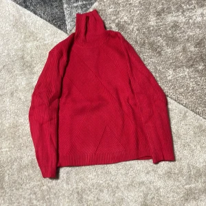 Röd ribbad tröja - Säljer en snygg röd polotröja med ribbad design. Tröjan har långa ärmar och en hög krage som håller dig varm under kyliga dagar. Perfekt för höst och vinter!