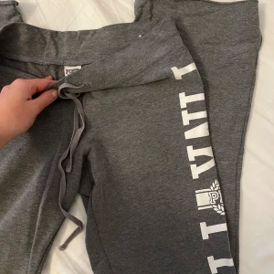 Lågmidjade utsvängda pink byxor  - Vintage utsvängda lågmidjade grå byxor från Pink (Victoria Secret) i storlek M. Fint skick enda defekt är en liten fläck på ena låret (se sista bilden)