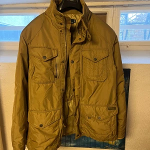 Beige/brun jacka från Polo Ralph Lauren - Säljer en snygg beige jacka från Polo Ralph Lauren. Jackan har flera praktiska fickor med knappar. Perfekt för höst och vår med sin quiltade insida som håller dig varm. Klassisk design med en touch av stil. Dragkedjan är sönder men går självklart att laga. 