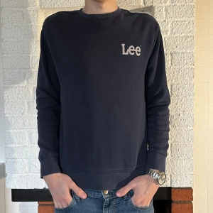 Mörkblå sweatshirt från Lee - Säljer en stilren mörkblå sweatshirt från Lee i regular fit. Tröjan har en rund halsringning och ett diskret Lee-tryck på bröstet. Perfekt för en avslappnad look.
