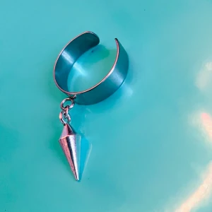 Made by prisförslag -ring med konformad hängsmycke - Stilrent silverfärgat och en unik konformad hängsmycke. Perfekt för att ge en edgy touch till din stil. Har en öppen design som gör det enkelt att bära.