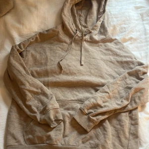 Beige hoodie i ekologisk bomull - Säljer en beige hoodie i ekologisk bomull från märket Cubus. Den har en klassisk design med huva och dragsko samt en stor ficka framtill. Perfekt för en avslappnad stil.