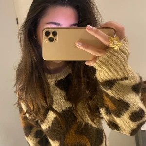 Beige leopardmönstrad stickad tröja - Säljer en mysig beige stickad tröja med leopardmönster i brunt och svart. Tröjan har långa ärmar och en avslappnad passform, perfekt för kyligare dagar. 🐆✨