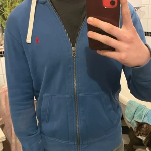 Blå zip tröja från Ralph Lauren - En riktigt snygg blå zip tröja i riktigt bra skick (skulle säga 9/10, hittar inga defekter). Insidan har skönt och varmt material som passar bra till våren, vintern, hösten eller kalla somma kvällar. Hör av er vid funderingar! 😁