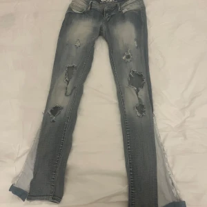 Blå jeans med spetsdetaljer från ONLY - Snygga blå jeans från ONLY med slitna detaljer och spets på bakfickan. De har en boutcut passform och väldigt  lågmidjat, passar mig som är cirka 168 och har xs-s i midja. Pris kan diskuteras 