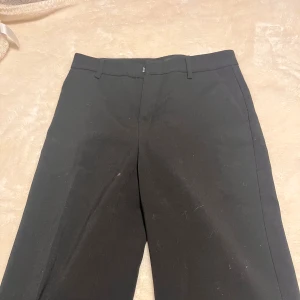 Svarta kostymbyxor från Gina Tricot - Snygga svarta kostymbyxor från Gina Tricot i storlek 34. Dessa byxor har jag bara använt ett fåtal gånger i samband med dansen under SM, annars nästan aldrig. Byxorna har en klassisk design. Perfekta för en stilren look. Knappen har dock lossnat, men dom funkar ändå super bra och ifall man vill kan man sy på en ny knapp. Tvättas innan den skickas och pris går alltid att diskutera 💞