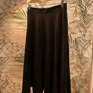 Svart kjol från Amisu - Elegant svart kjol från Amisu i en klassisk design. Kjolen har en plisserad stil som ger ett stilrent och tidlöst intryck. Perfekt för att skapa en chic look.