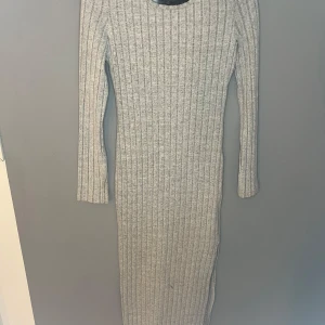 Grå ribbad klänning - Snygg grå ribbad klänning med lång ärm och rund hals. Perfekt för kyligare dagar med sin mysiga och stilrena design. Passar både till vardags och mer uppklädda tillfällen. 