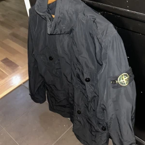 Svart jacka från Stone Island -  Stone Island jacka i sällsynt syntetmaterial. Äkta✔️, skick 8/10, endast använt på ett par matcher sedan 2022 då ja köpte den helt ny. Jackan har även Micro spesefickation som betyder att den är en del av en kollektion som är gjord i samma material som brittiska militärens uniformer. Kan gå ner i pris vid snabb affär. Ny pris ca,6-7. Hör av dig vid minsta fråga✔️