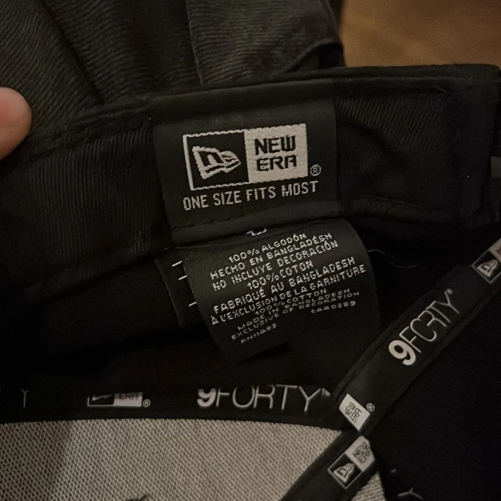 Snygg svart keps från New Era med den ikoniska NY-loggan broderad i vitt framtill. Kepsen är justerbar och tillverkad i 100% bomull, vilket gör den bekväm att bära. Perfekt för en casual look.. Asusteet.