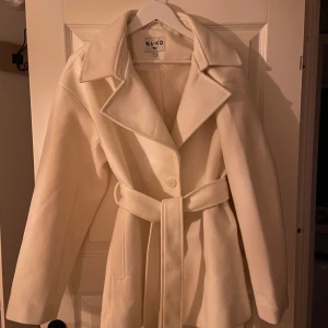 Kappa från NA-KD - Jätte fin kappa från NA-KD, stl 38, ljus beige/vit, aldrig använd, säljer den för 400kr