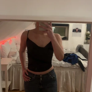 Svart linne med snörning - Snyggt svart linne med smala band och snörning i ryggen. Perfekt för en stilren och trendig look. Passar bra till både jeans och kjol. Pris kan diskuteras 