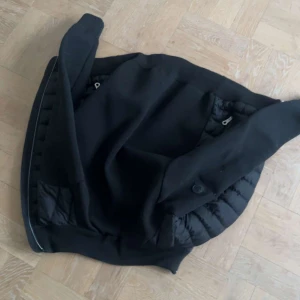 Moncler Cardigan Padded Up Svart - Snygg svart jacka med quiltade detaljer och dragkedja. Perfekt för en stilren look. Jackan har långa ärmar och en modern design.