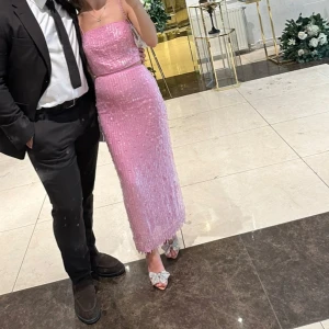 Rosa topp och kjol med paljetter och pärlor. - Säljer en glittrig rosa topp och kjol med paljetter och pärlor. Elegant passform som framhäver figuren. Perfekt för festliga tillfällen.