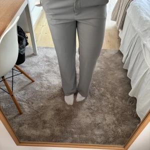 Grå kostymbyxor från NA-KD - Snygga grå kostymbyxor från NA-KD med medelhög midja, rak passform och slit. Mycket bra skick då dem endast är använda ett par gånger!