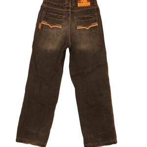 Svarta jeansbyxor från Error - Snygga svarta jeansbyxor från Error med coola detaljer på bakfickorna.               Storlek:5 Benlängd:103 Midja:38 Gylf:30 Fotöppning:22 Lår:25 