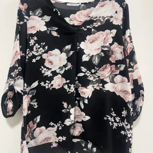 Svart blommig blus från Hailys - Snygg svart blus från Hailys med ett vackert blommönster i rosa och vita nyanser. Blusen har trekvartsärmar och en lös passform, perfekt för en stilren look. Skriv för fler bilder eller om ni har fler frågor 💓