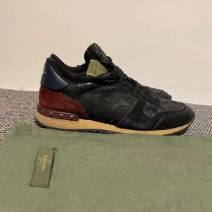 Svarta sneakers från Valentino - Snygga svarta sneakers från Valentino med stjärnmönster och detaljer i rött och beige. Bra skick i storlek 45. Valentino är true to size så om du har 45 köp oftast 45 för att få rätt storlek. Nypris runt 5500 kr. Finns ute på Sicuro också 