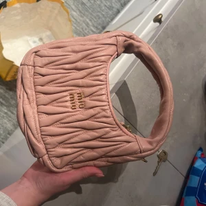 Rosa axelväska från Miu Miu - Säljer en snygg rosa axelväska från ” Miu Miu ”med quiltad design. Väskan har en praktisk dragkedja och är perfekt för att ge din outfit en lyxig touch. Den är kompakt och stilren, vilket gör den till ett måste i garderoben. Köpte i Paris på en marknad, dem sa att den var äkta men hade inga bevis. 
