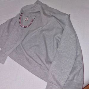 Grå hoodie och byxor från Moncler - Säljer en grå hoodie och matchande byxor från Moncler. Hoodien har långa ärmar och en klassisk design med Moncler-logga. Byxorna har elastisk midja och Moncler-logga på benet. Den passar perfekt till din kroppsform. Storleken är medium. Det finns inga defekter eller skador på denna tracksuit. Det finns en tagg innanför tröjan som tar dig direkt till monclers hemsida! Kan mötas upp i rydsgård skurup eller svedala. Kontakta för mer information!