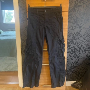 Svarta cargobyxor - Säljer ett par svarta cargobyxor med knappstängning och flera fickor. Byxorna har en loose passform och passar både till vardags och finare tillfällen 💛