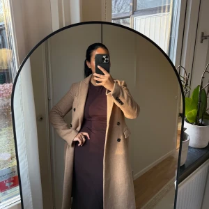 Beige kappa med knappar från Zara  - Snygg beige kappa med dubbelknäppning och långa ärmar. Perfekt för höst och vår, med en klassisk design som passar till många outfits. I en ull blandning så den är varm & skön och i otroligt fint skick. Från Zara i storlek 34