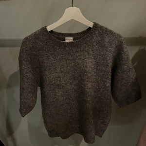 Grå stickad tröja från Stories - Säljer en stilren grå stickad tröja från Stories. Tröjan har en klassisk rund hals och korta ärmar, perfekt för lager-på-lager under kyligare dagar. En tidlös baströja som passar i alla garderober.