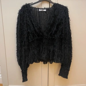 Svart fluffig blus - Säljer en svart fluffig blus med v-ringning och långa ärmar. Köpt på på plick men aldrig använd av mig💞 