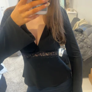 Svart  blus  - Elegant svart blus från Gina.Den har en vacker spetsdetalj i midjan som ger en feminin touch. Perfekt för en stilren look. Skriv privat för fler frågor eller bilder🥰