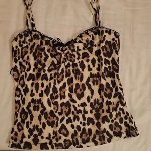 Leopardmönstrad linne från Gina Tricot - Snygg leopardmönstrad linne från Gina Tricot med spetsdetaljer och en liten rosett framtill. Sitter tajttt. Justerbara axelband för bästa passform.  Någon lös tråd, se på bild 2 och 4. Storlek XXS 💞 köptes för 260 kr